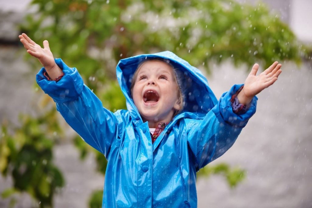 Glad dreng i regnvejr, iført foret regntøj