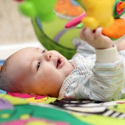 Baby leger med legetøj i sin aktivitetstæppe
