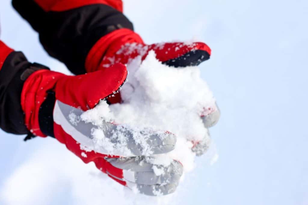 Røde vinterhandsker, der omfavner en snebold