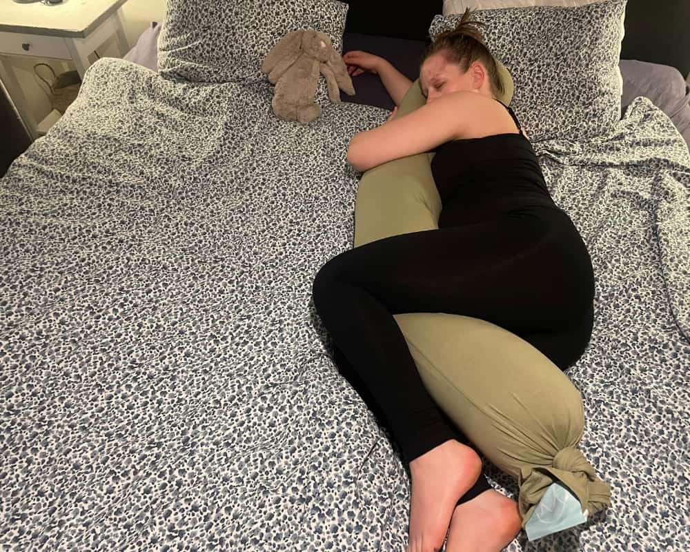Kvinde ligger i sengen med Najell graviditetspude